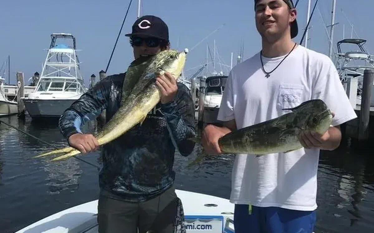 Two anglers holding mahi mahi caught offshore on a South Florida fishing charter - Nomad Fishing Charters