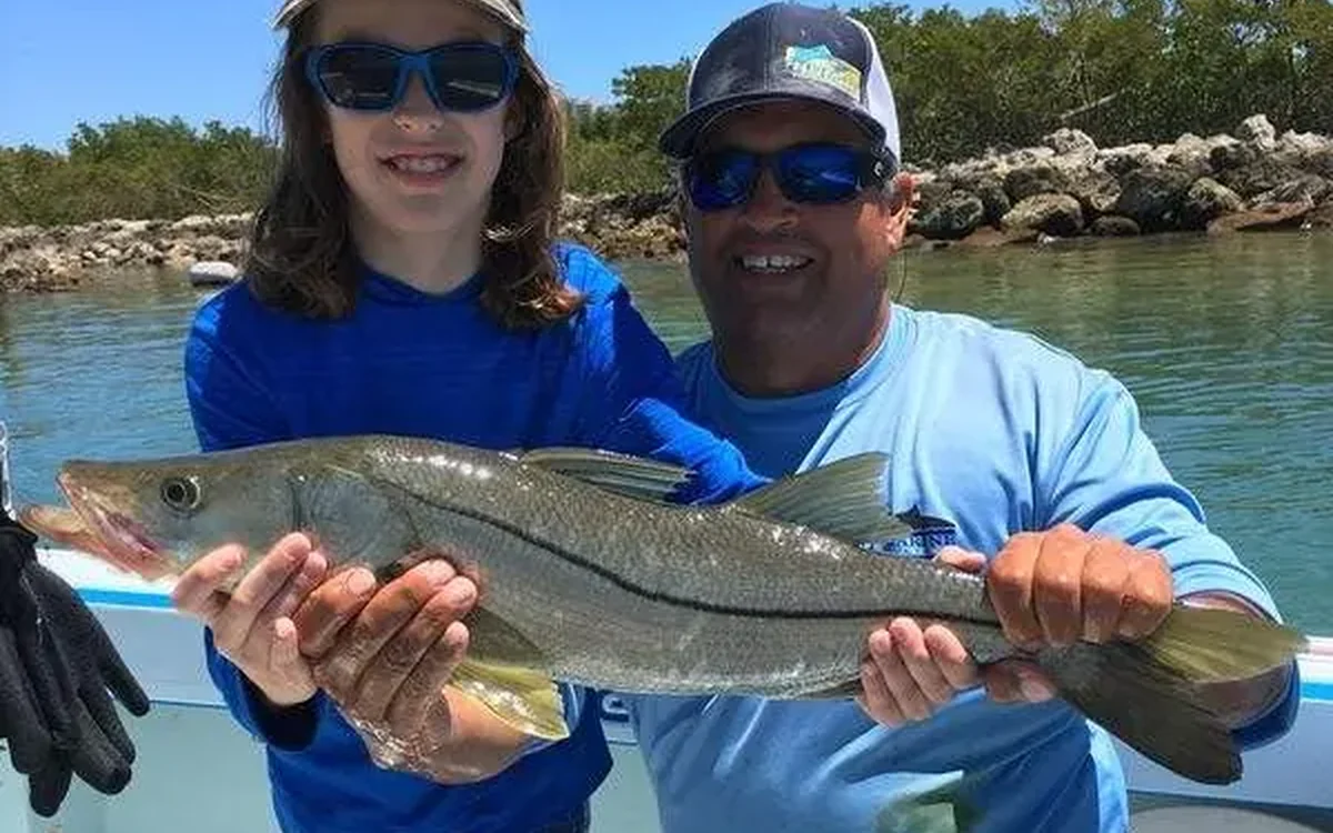 Young angler and guide holding a snook caught on a calm inshore charter - Nomad Fishing Charters